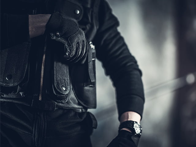 Security guard in black pulling pistol